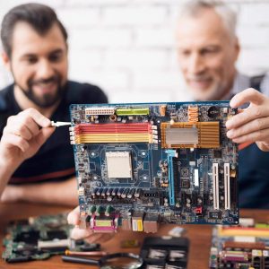 Computer Engineers Examine PC Board Component.